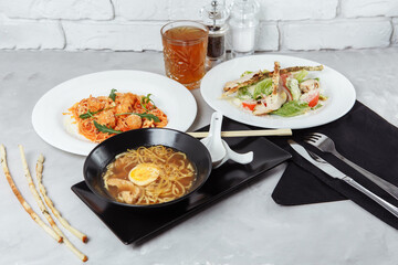 three-course set on a table in a restaurant, cafe menu. Business lunch from bowl ramen with chicken and egg, fresh caesar salad and pasta