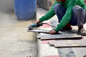 Fototapeta na wymiar Builder worker with grinder machine cutting metal parts at construction site