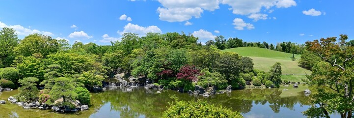Fototapeta na wymiar 青空バックに新緑に包まれた日本庭園のパノラマ情景＠大阪