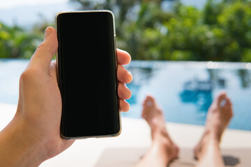 Smartphone in hand closeup on pool background