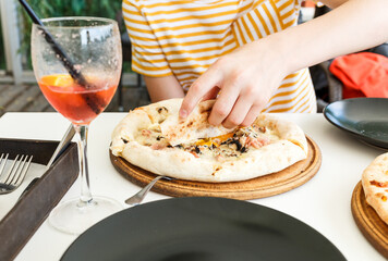Young boy eating pizza. Teenager taking a piece of pizza with mushrooms and cheese. Still life, dinner in cafe, pizzeria. Close up	