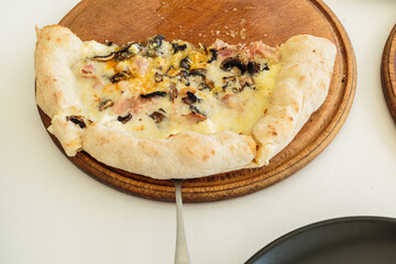 homemade pizza with cheese on wooden tray.