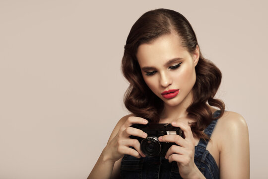 Girl in pin-up style holds a retro camera in her hand.