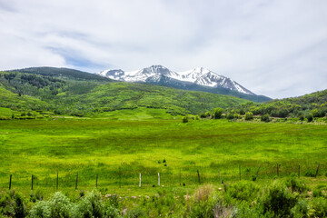 Carbondale, USA grass ranch fence view of snow on Mt Sopris in Colorado with rocky mountain peak and open pasture field in Roaring Fork Valley