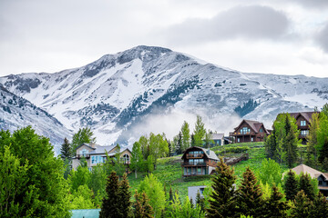 Crested Butte, USA Colorado village in summer with clouds and foggy mist morning and houses on hillside with green trees