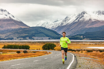 Athlete runner running road race in amazing mountain range landscape in New Zealand. Man run...