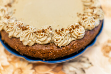 Whole yellow vanilla and caramel chocolate dessert homemade cake with brown frosting and decoration on vintage tablecloth and plate macro closeup