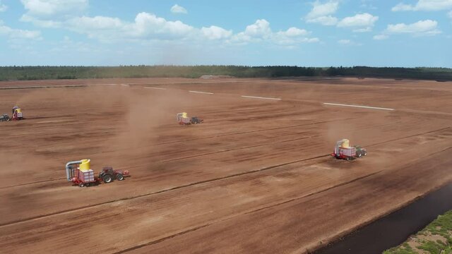 Aerial view of industrial peatlands with extraction tractors working on the field. Peat production landscape. 4k footage. Forward motion.