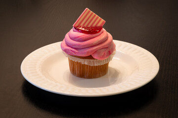Patriotic homemade raspberry and vanilla cupcake with American flag chocolate decoration for Fourth of July (American Independence Day).