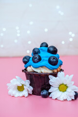 vertical photo of a festive dessert cupcake with blue cream and blueberries