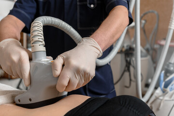 Professional cosmetologist using vela shape machine on client's belly during anti-cellulite procedure