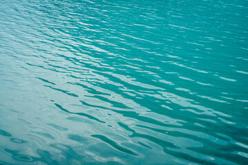 Texture of azure calm water of mountain lake. Meditative ripples on water surface. Nature minimal background of turquoise lake. Natural backdrop of clear cyan water. Full frame of lake fragment.