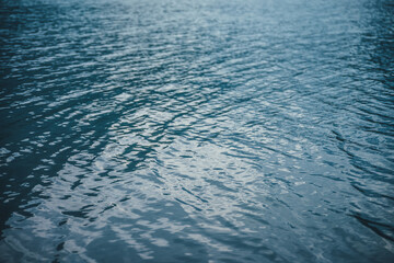 Texture of purple calm water of mountain lake. Meditative ripples on water surface. Nature minimal background of violet lake. Natural backdrop of clear dark blue water. Full frame of lake fragment.