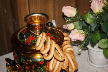 Russian Khokhloma samovar is on the table, hanging on it a bunch of yellow bagels. Image with selective focus