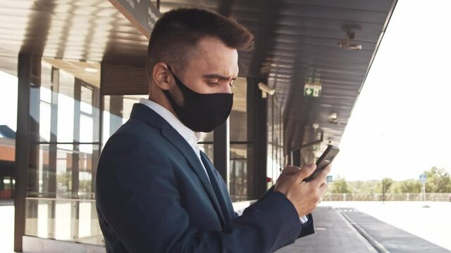 Elegant businessman wearing protective mask in airport. Young mail entrepreneur in formalwear. Pandemic, new rules of control, business trip and traveling.