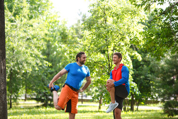 Naklejka premium Two men warming up muscles before jogging outdoor.