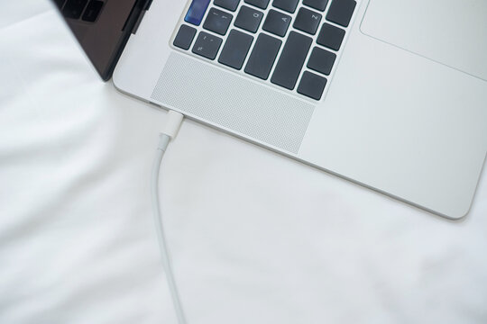 Computer Laptop Charging Battery On Bed In The Bedroom At Home. Technology, Multiple Sharing Charger And Lifestyle Concepts