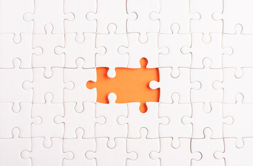 Top view flat lay of paper plain white jigsaw puzzle game texture incomplete or missing piece, studio shot on an orange background, quiz calculation concept