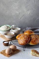 Burger buns covered with sesame seeds on baking grid and ingredients, Vertical orientation, copy space