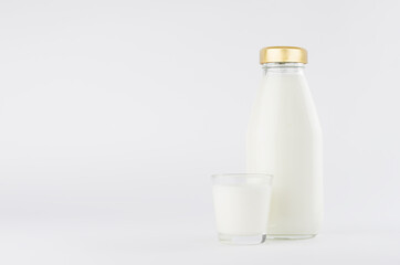 Fototapeta na wymiar Milk in glass bottle with golden cap template with glass on white background with copy space, mockup.