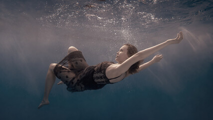Fototapeta na wymiar Portrait of a girl in a dress floating underwater