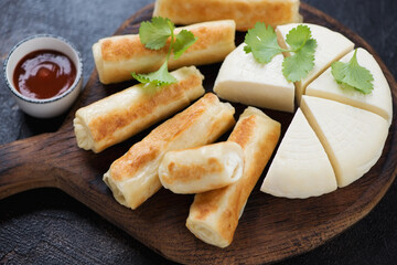 Close-up of roasted georgian crepes stuffed with suluguni cheese on a rustic wooden serving board, selective focus