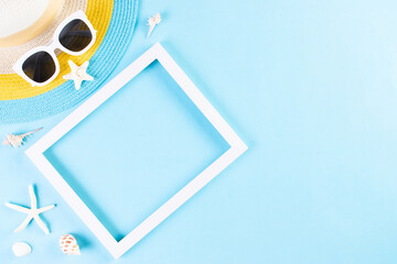 Summer or vacation concept. Beach hat and  sunglasses with photo frame on light blue background. Copy space.
