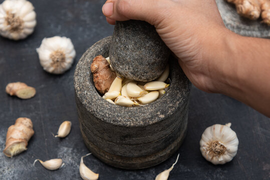 Ginger garlic paste with mortar and pestles homemade paste spicy herb ingredient of Thai Asian food. Fresh mashed Adrak and Lahsun on dark black background