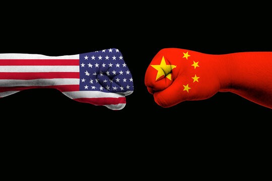 Flags of USA and China painted on two fists on black background.
