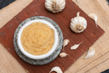 Ginger garlic paste with mortar and pestles homemade paste spicy herb ingredient of Thai Asian food. Fresh mashed Adrak and Lahsun on dark black background