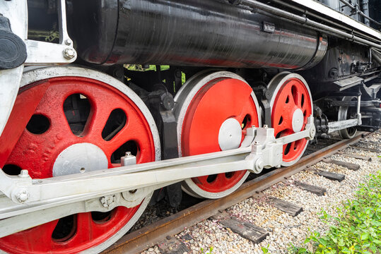 Red wheels of a steam train locomotive are seen on the train station railway
