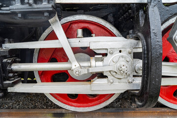 Red wheels of a steam train locomotive are seen on the train station railway