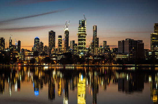 The reflections of the melbourne city skyline at dusk in the still water of albert park lake