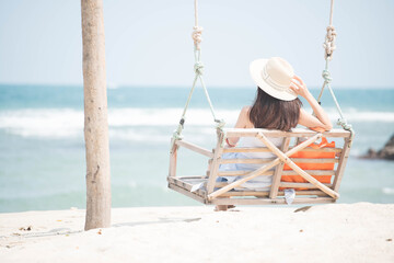 Fototapeta premium A woman sitting on a swing And looking at the sea on the beach