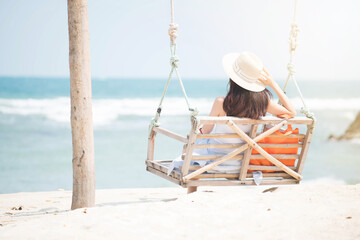 A woman sitting on a swing And looking at the sea on the beach