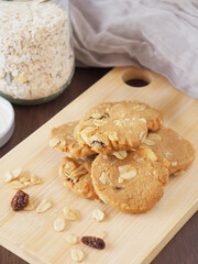 Healthy homemade oat cookies on wooden boards with a bottle and fabric in the background..