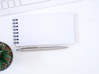 Top view, flat lay notebook and pen with the keyboard on modern white desk, business concept with space for your text..