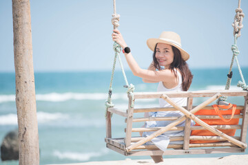 Asian woman sitting on a swing And looking at the sea on the beach