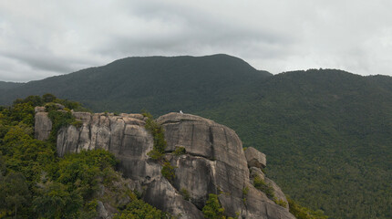 Man on top of rock with mountains on background