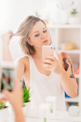 sexy girl with tattoos taking selfie photo on phone in bathroom mirror.