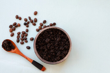 Top view of jar with roasted coffee bean scrub with wooden spoon and sea salt on mint background. Rejuvenating coffee scrub in round jar for skin exfoliation.
