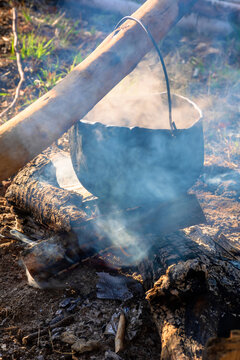 steaming old pot outdoor. cooking and camping. outdoor adventures concept. beaten cauldron on camp fire