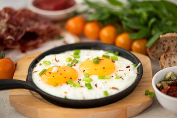 two fried eggs with herbs and spices in a small skillet