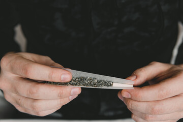 Cannabis use concept. Close up of marijuana blunt with grinder. Preparing and rolling marijuana...