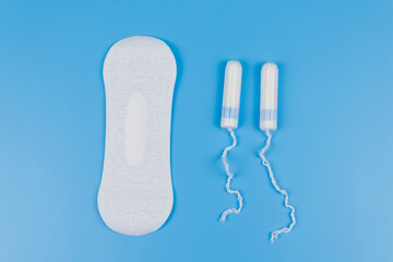 Sanitary pad and tampons on blue background. Top view