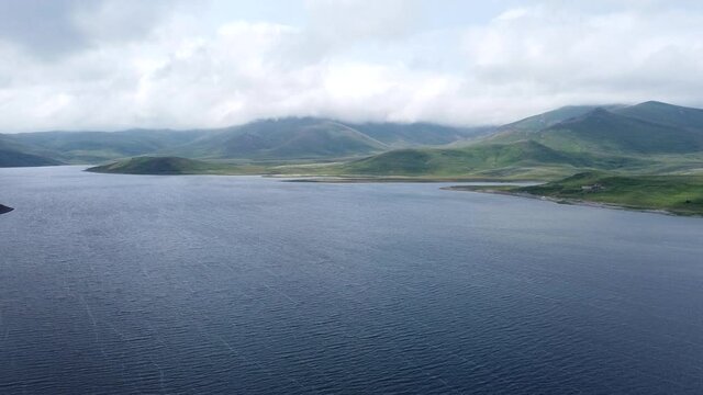 Aerial Drone shot of Lake, surrounded by hills and mountains. One of the biggest crystal pure water reservoirs in the world, located in Armenia, Caucasus.