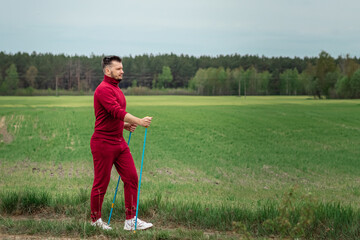 Fototapeta premium A man in a tracksuit is engaged in Nordic walking. The concept of a healthy lifestyle, cardio training. Copyspace.