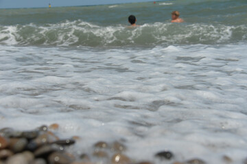average waves on the sea reach the shore with foam and crash on the rocks with a noise