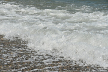 average waves on the sea reach the shore with foam and crash on the rocks with a noise