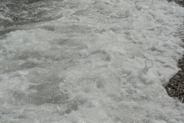 average waves on the sea reach the shore with foam and crash on the rocks with a noise
